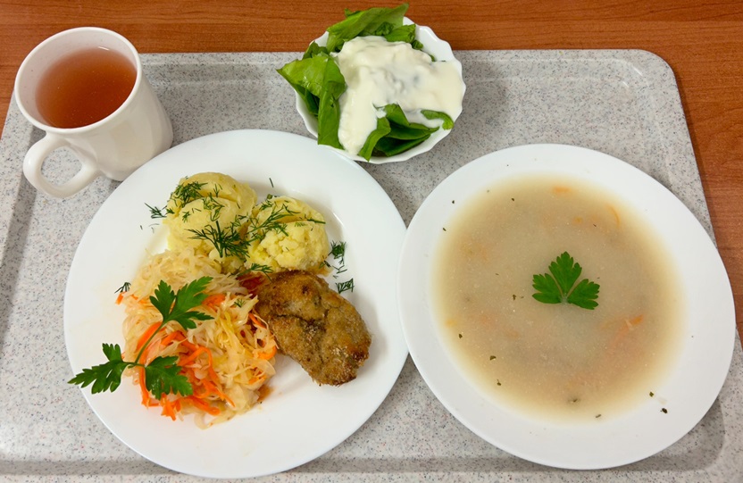 Na zdjęciu znajduje się: Krupnik jęczmienny, Ziemniaki, Kotlet z ryby (Dorsz), Surówka z kapusty kiszonej z olejem, Kompot owocowy, Sałata zielona z jogurtem